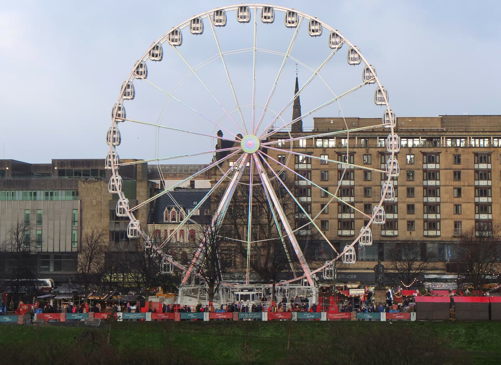 The LNER Big Wheel rising above the Christmas market chalets in East Princes Street Gardens at dusk