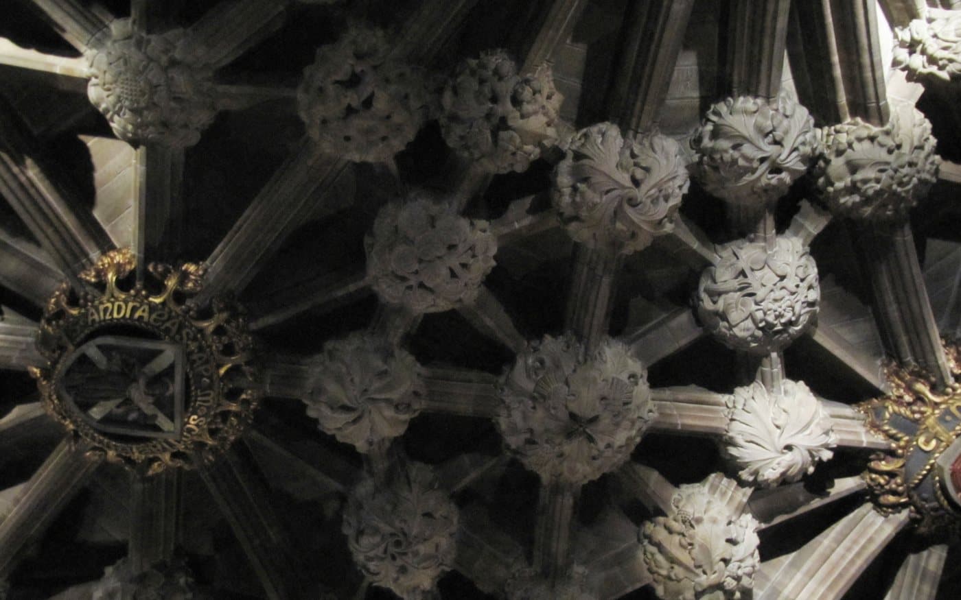 The carved stone vault of the Thistle Chapel in St Giles' Cathedral, dense with foliage bosses and a gilded knight's crest set into the ribs